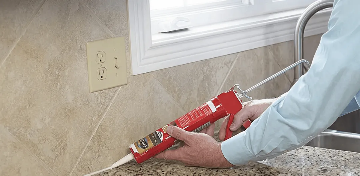 Handyman applying caulk along a kitchen backsplash and countertop seam in Baltimore, MD