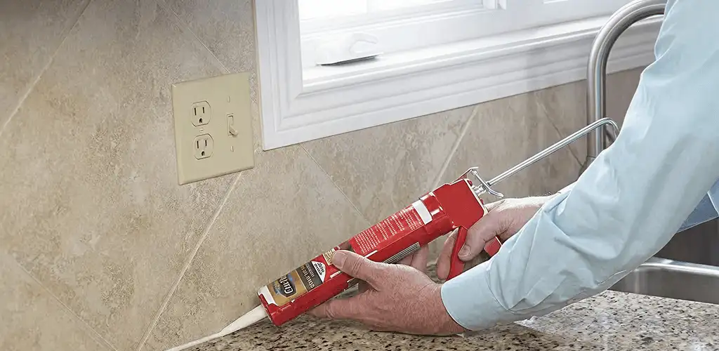 Handyman applying caulk along a kitchen backsplash and countertop seam in Baltimore, MD