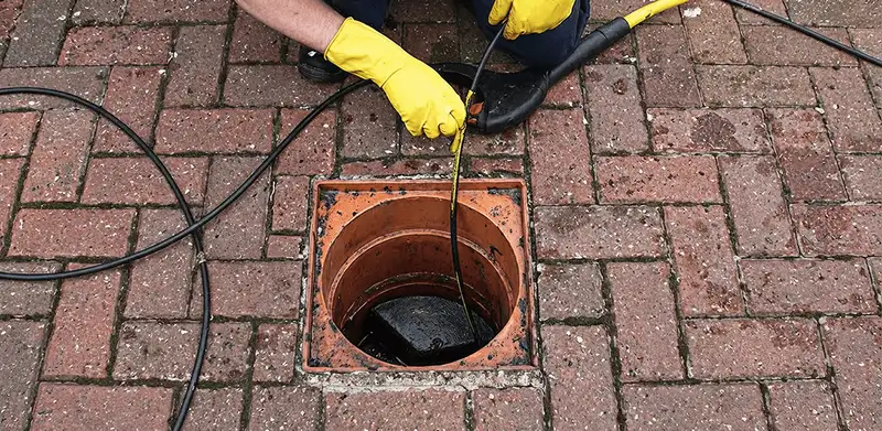 Drain cleaning technician using a drain snake to clear a clogged drain in Baltimore, MD
