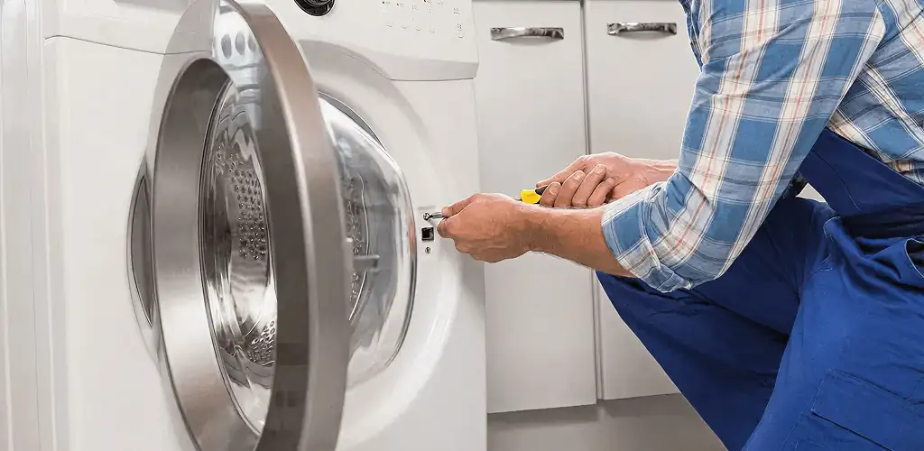 Handyman repairing a clothes dryer and checking electrical connections in Baltimore, MD