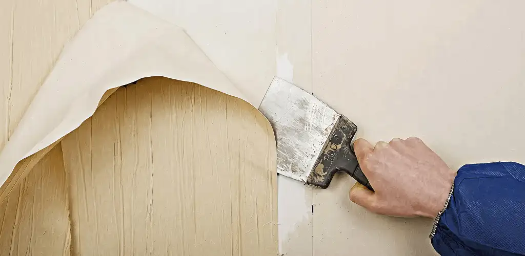 Handyman removing wallpaper with a scraper for wall preparation in Baltimore, MD