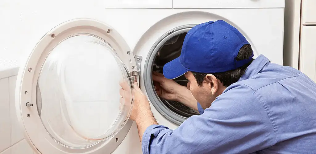 Washing machine repair handyman inspecting a front-load washer drum in Baltimore, MD