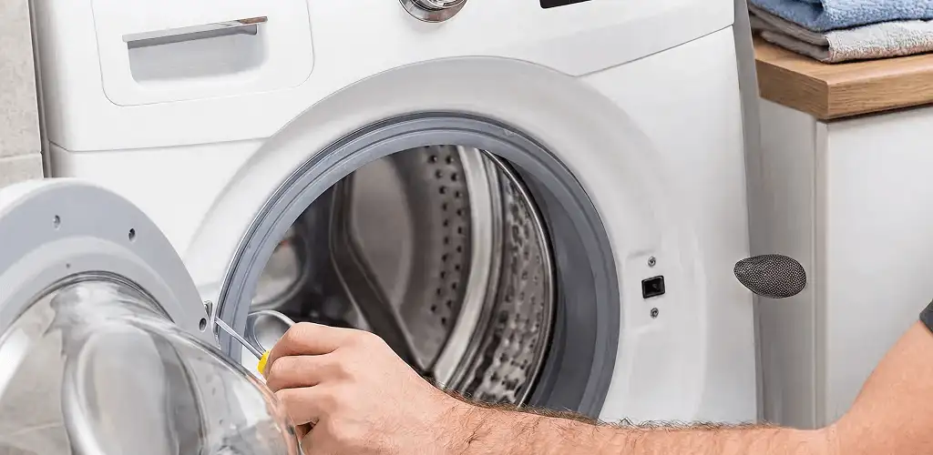 Handyman repairing a front-load washing machine and inspecting the drum in Baltimore, MD